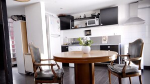 A modern kitchen with a round wooden table, two chairs, a microwave, and a stove. - central sun loft- door of the sun (MADRID)