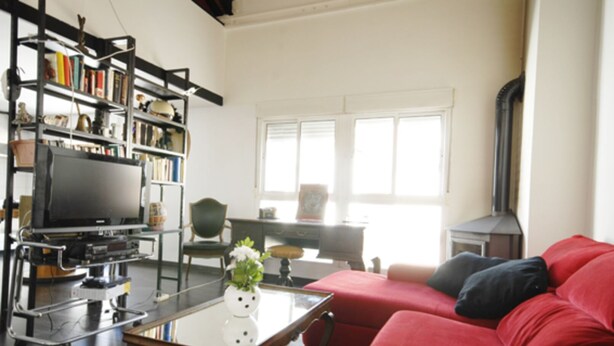 A living room with a red sofa, a television on a cart, a bookshelf, and a fireplace. - central sun loft- door of the sun (MADRID)