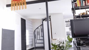 A modern interior with a staircase, a bookshelf, and a decorative hanging. - central sun loft- door of the sun (MADRID)