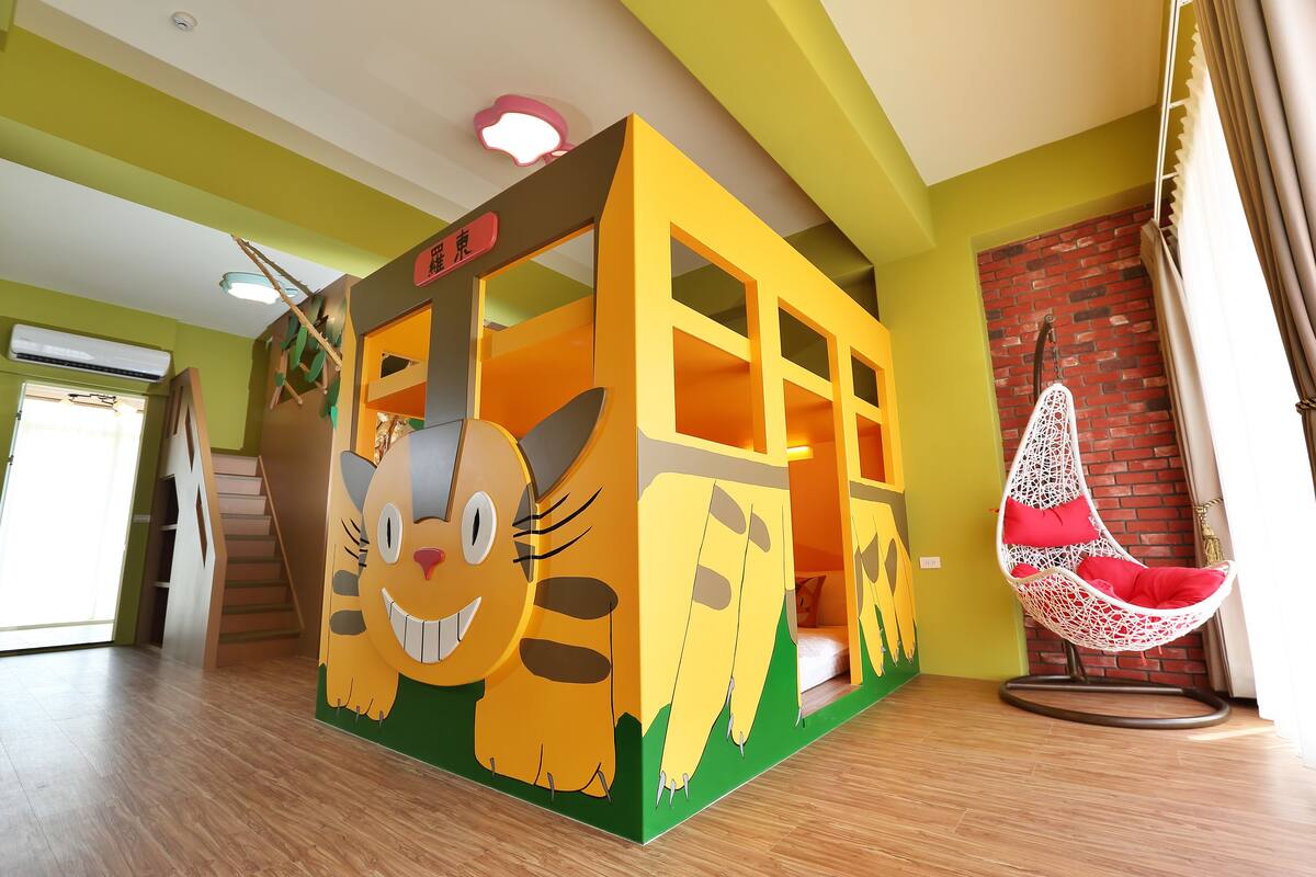 A children's play area with a large cat-themed playhouse, a hanging chair, and a staircase.