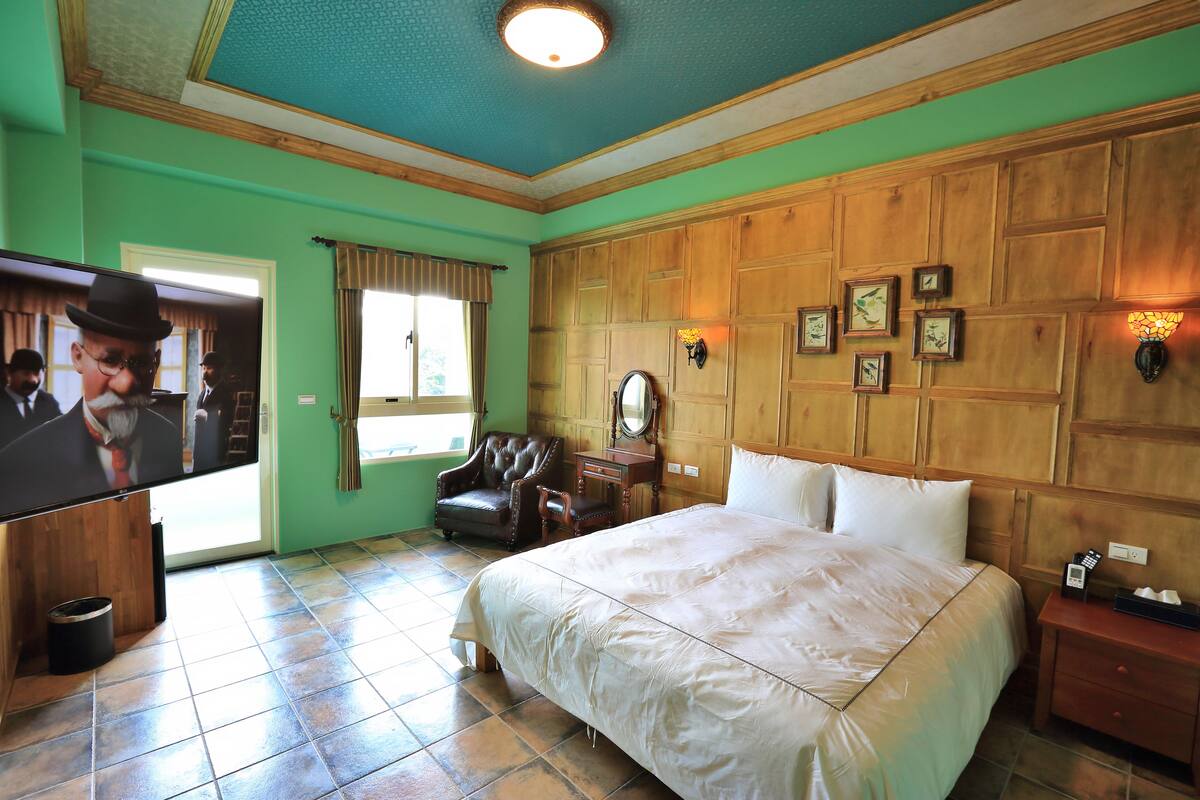A hotel room with a large bed, a television, a wooden headboard, and a wooden wall paneling.