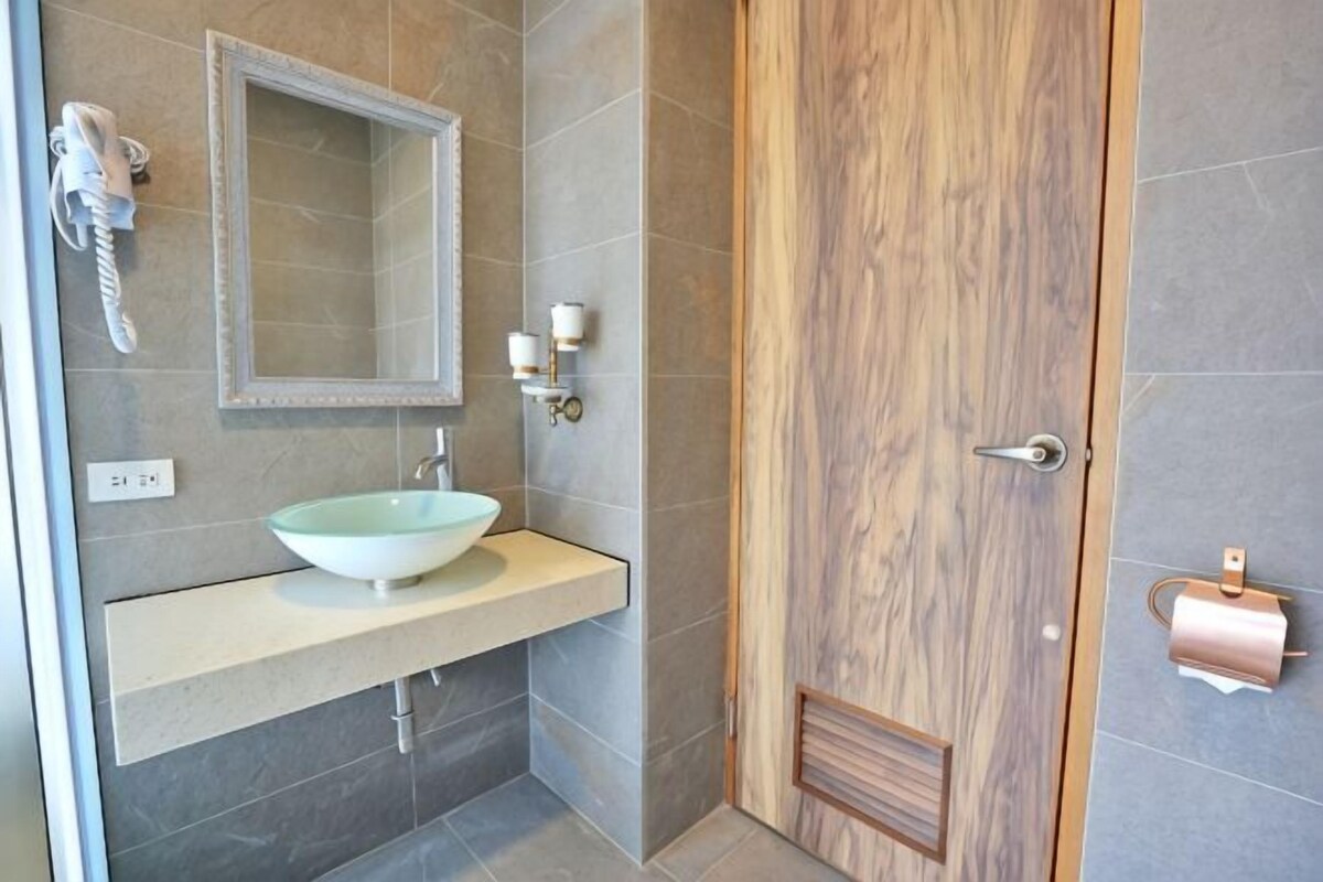 A bathroom with a sink, mirror, and towel dispenser.