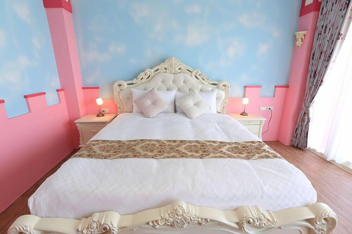 A large bed with a tufted headboard, two bedside lamps, and a decorative bed runner.