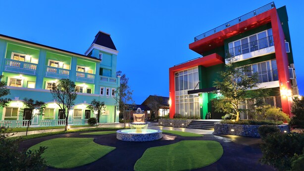 A hotel with a fountain in the courtyard, surrounded by well-maintained lawns and pathways. - Green Resort (Wujie)