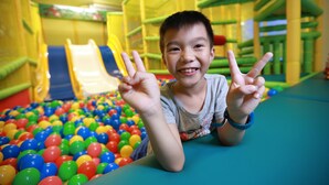 A child in a play area with colorful balls and slides. - Green Resort (Wujie)