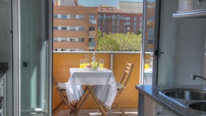 Ein Balkon mit Tisch und Stühlen für zwei Personen, sowie ein kleiner Tisch mit Flasche und Gläsern.