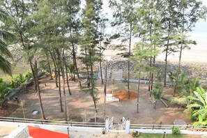 A view of a beach area with trees, a sandy path, and a gate leading to the beach. - Sea Princess Beach Resort (Dapoli)