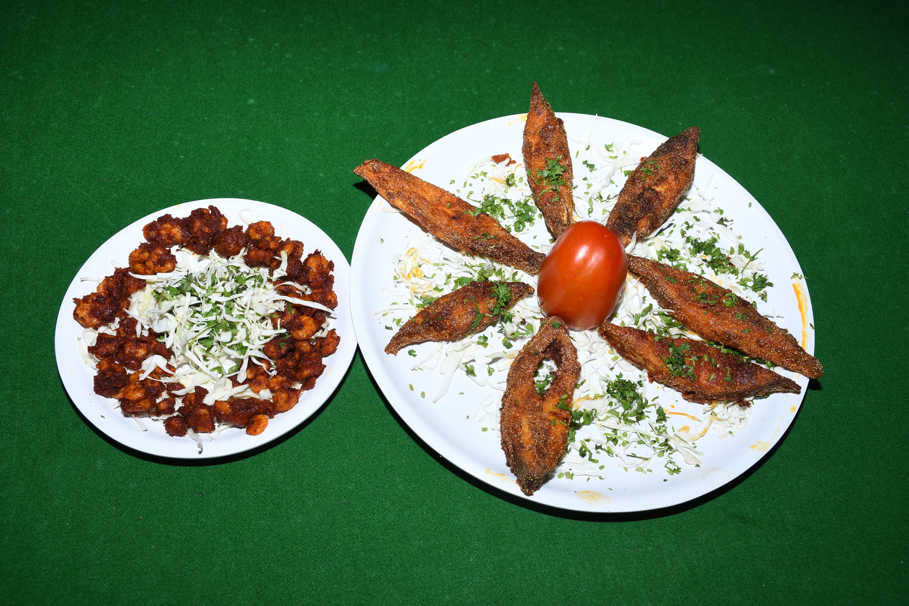Two plates of food on a green tablecloth.