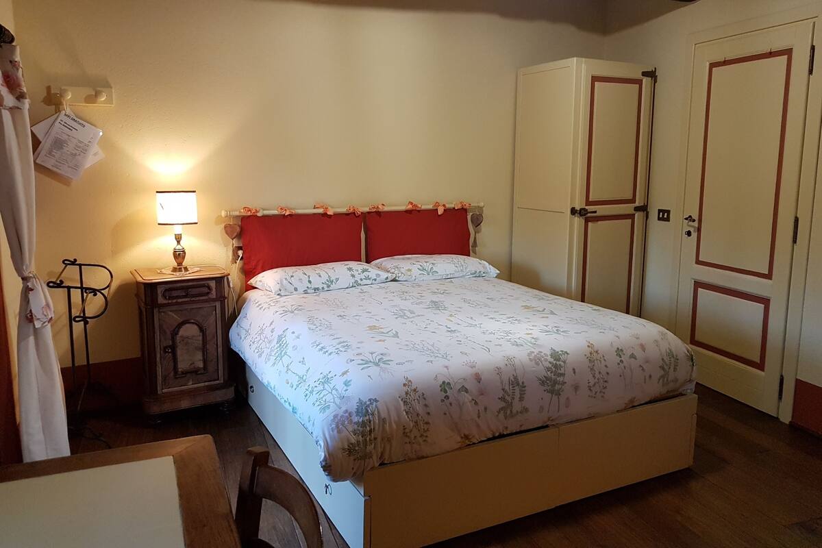 Une chambre à coucher avec un lit, une table de chevet, une lampe, une armoire et une porte.