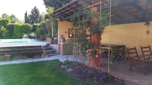 Un espace extérieur aménagé avec une piscine, des sièges, et un jardin agrémenté de diverses plantes et fleurs.