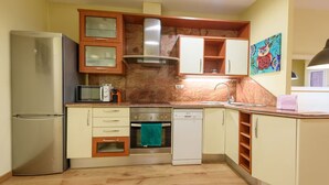 A compact kitchen with a refrigerator, microwave, oven, and dishwasher.