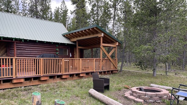 A log cabin with a wooden deck and a covered porch.