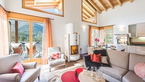 A spacious living area with a fireplace, large windows, and a view of the outdoors. - Chalet Alpharmonie (Zermatt)