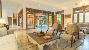 Amplia sala de estar con una mesa de centro de madera, asientos cómodos y grandes ventanas que ofrecen vistas al exterior.