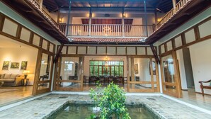 Un espacio interior amplio con un elemento central de agua, balcones de madera y un área de comedor.