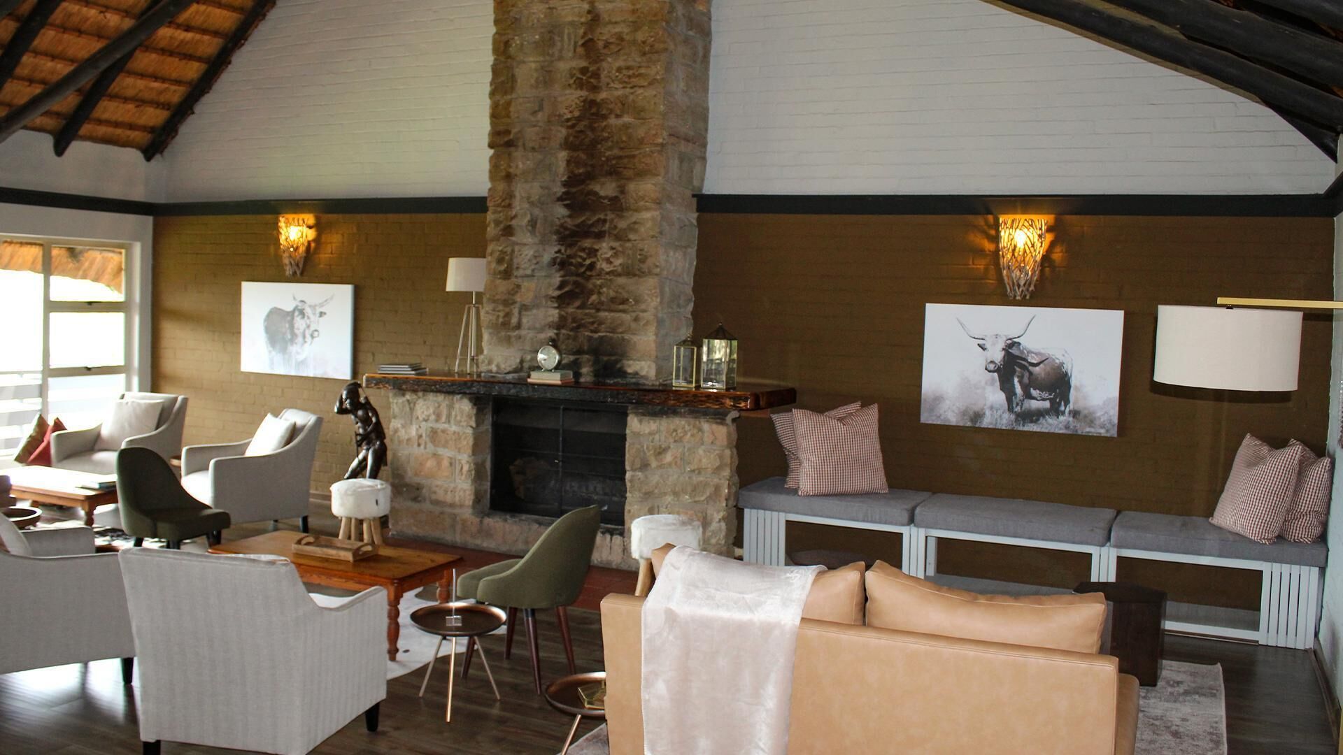 A cozy living room with a stone fireplace, comfortable seating, and artwork on the walls.
