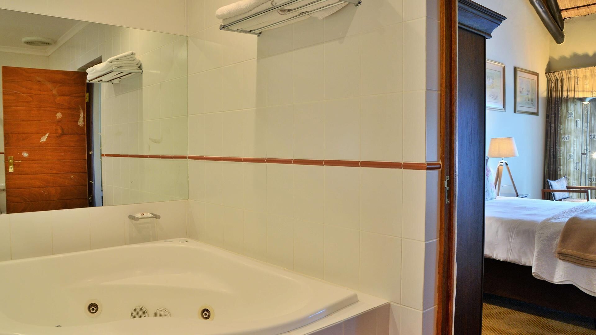 A bathroom with a bathtub, a mirror, and a towel rack.