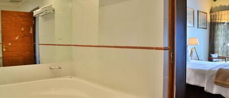 A bathroom with a bathtub, a mirror, and a towel rack.