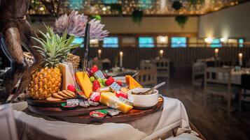 A buffet table with various cheeses, fruits, and crackers.