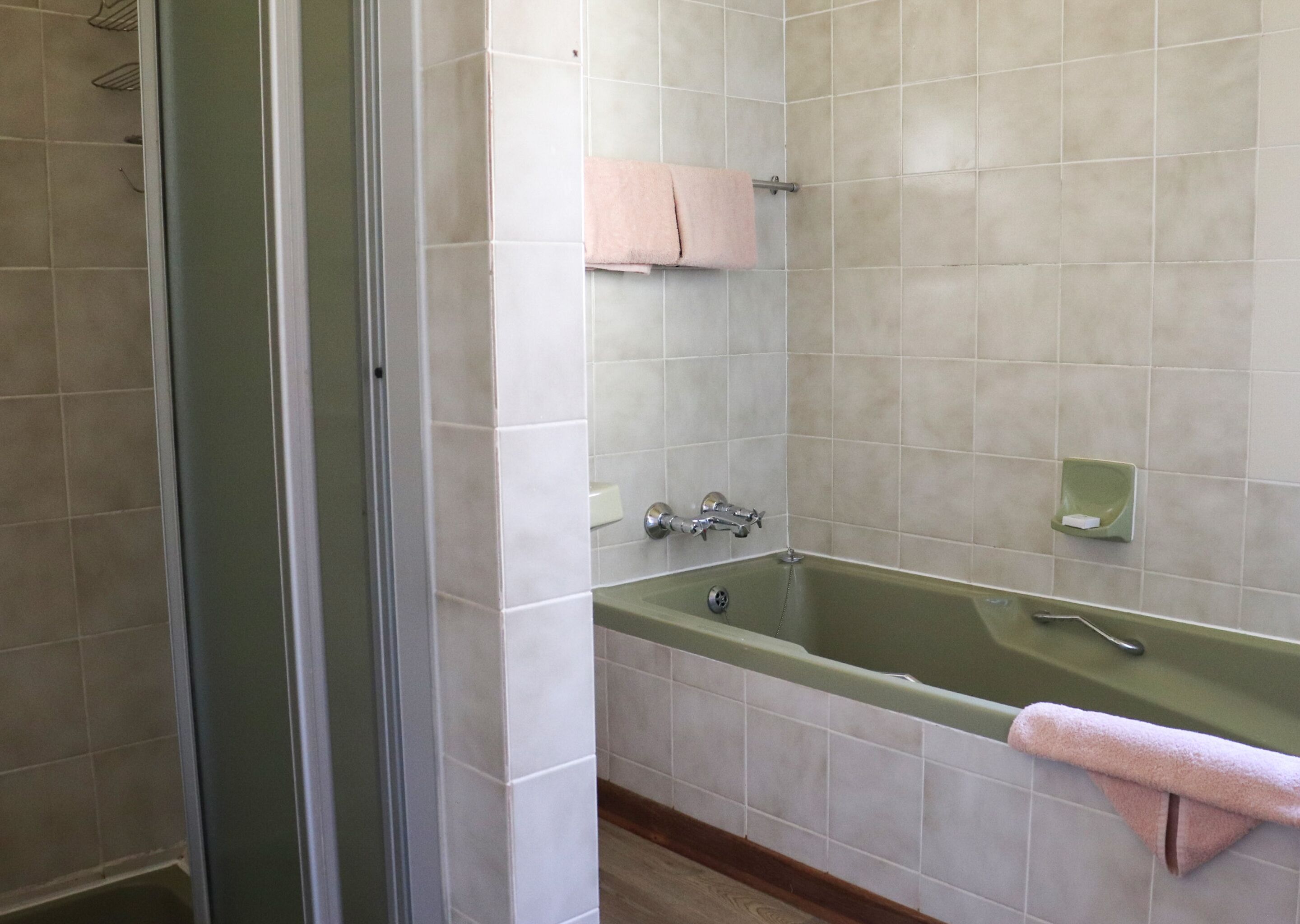 A bathroom with a green bathtub, a towel rack, and a soap dish.