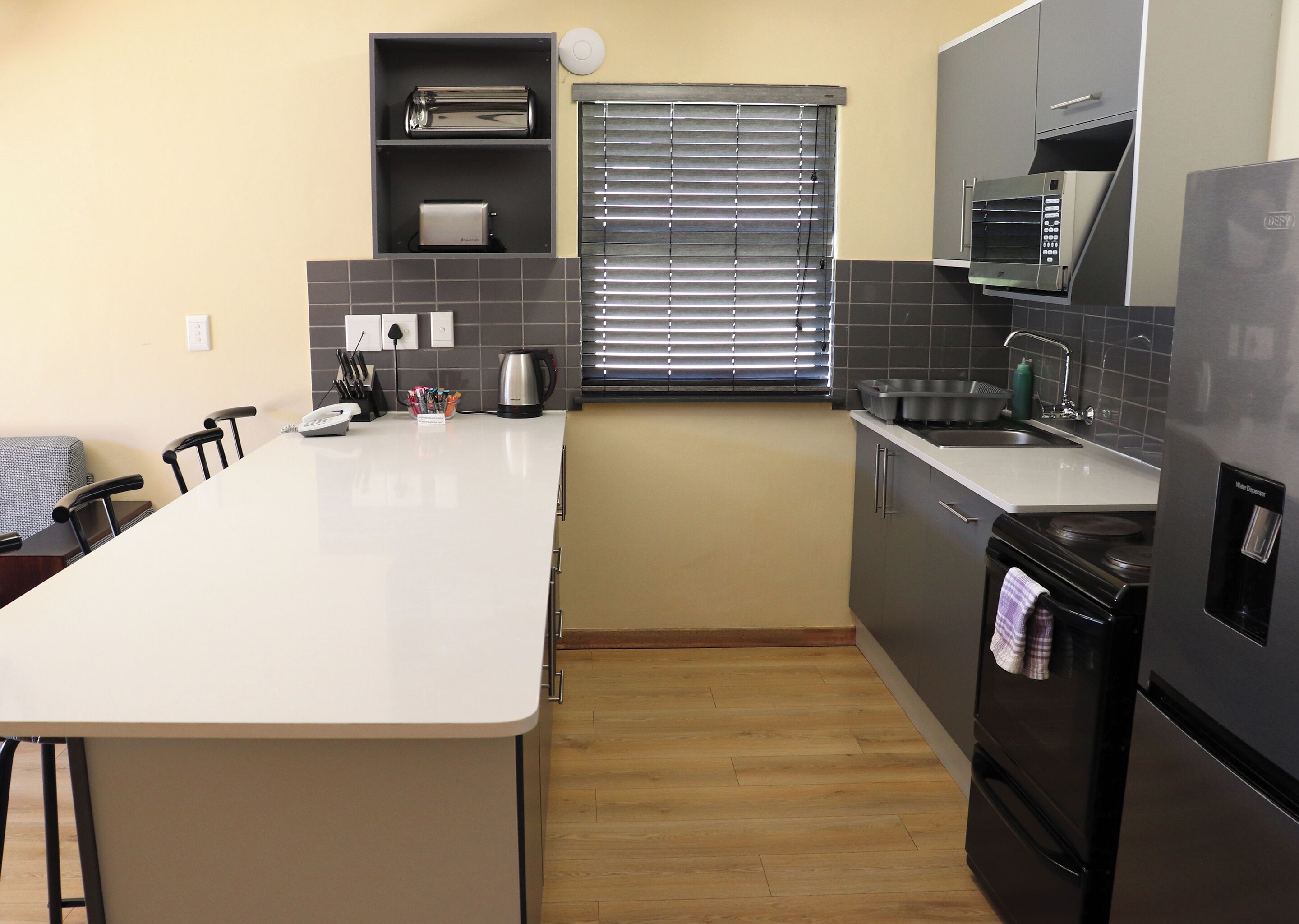 A modern kitchen with a central island, a built-in oven, a microwave, and a water dispenser.