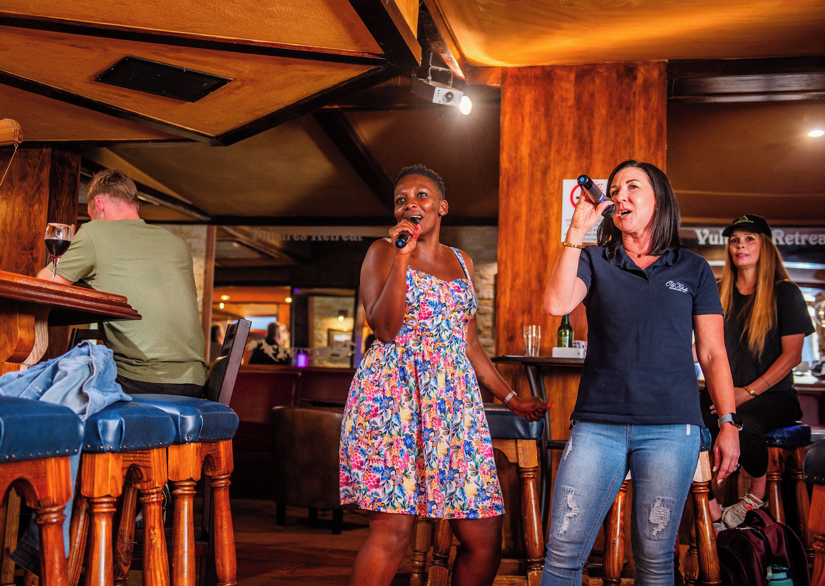 A bar area with wooden furniture and a person singing into a microphone.