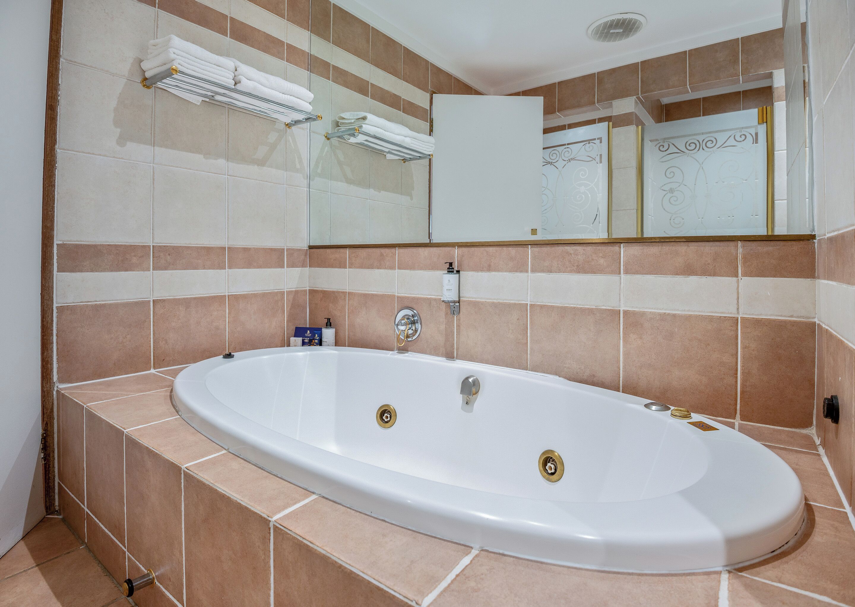 A bathroom with a large oval bathtub, a glass shower enclosure, and a white cabinet with a decorative mirror.