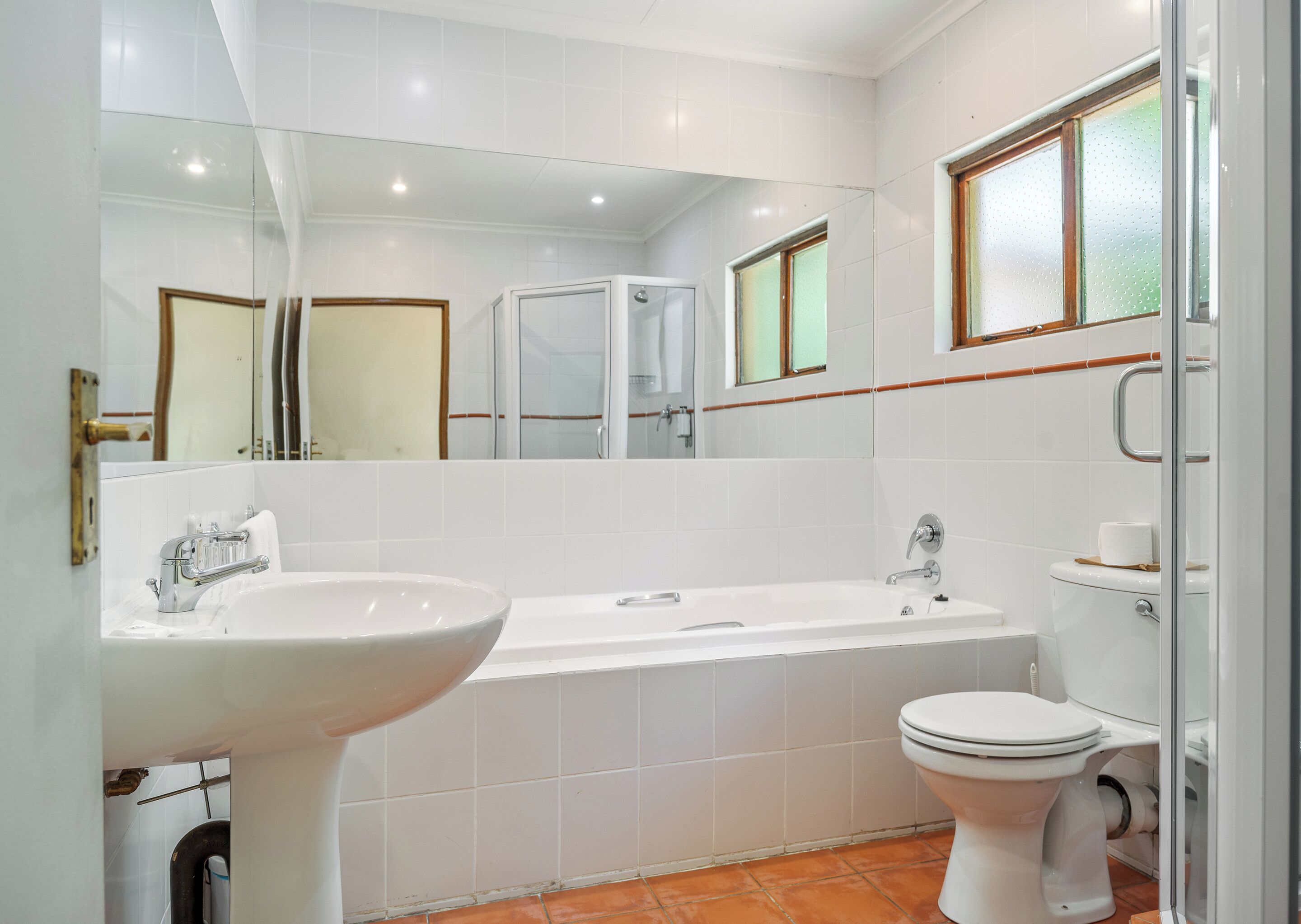 Een moderne badkamer met een wit wastafel, bad en toilet.