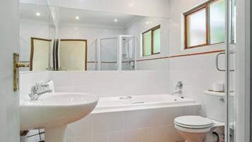 Een moderne badkamer met een wit wastafel, bad en toilet.