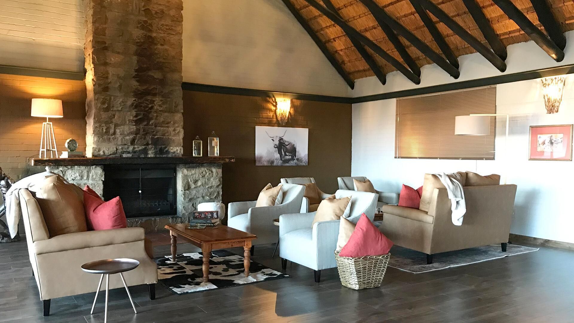 A spacious living room with a stone fireplace, leather sofas, and a high ceiling with exposed beams.