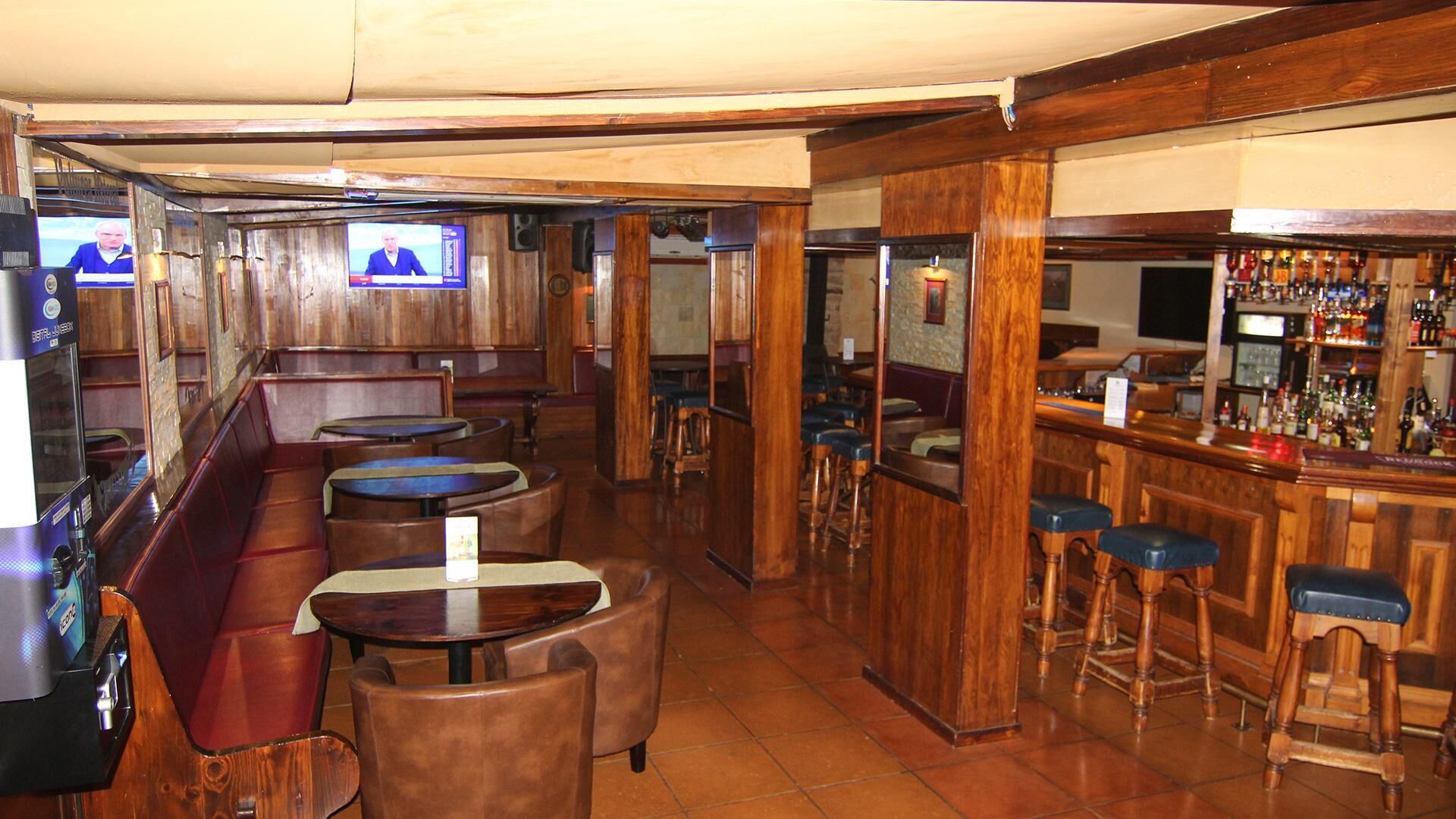 Een bar met houten meubels, een bargedeelte en een televisiescherm.