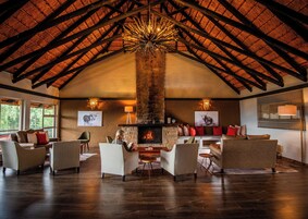 Una habitación amplia con techo de madera alto, chimenea y varias zonas de estar.