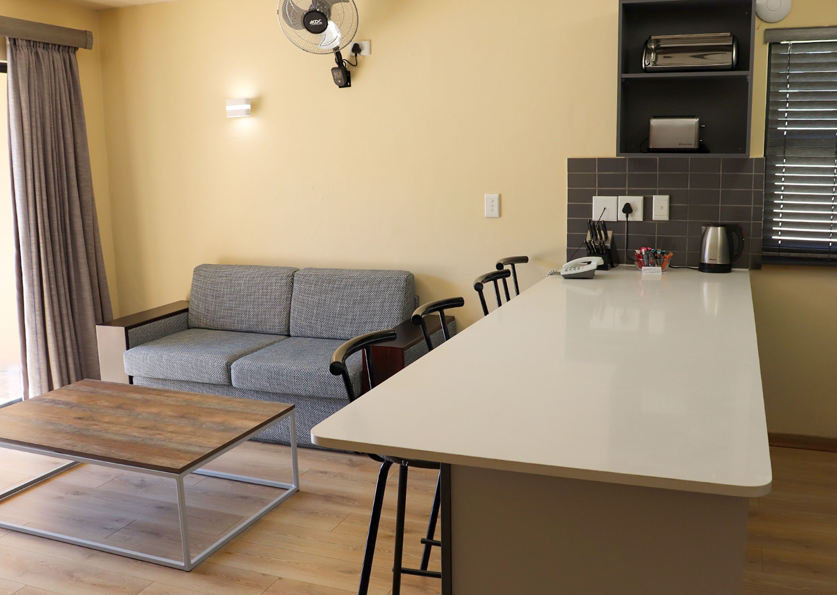 A modern kitchen with a central island, a grey sofa, and a dining table.