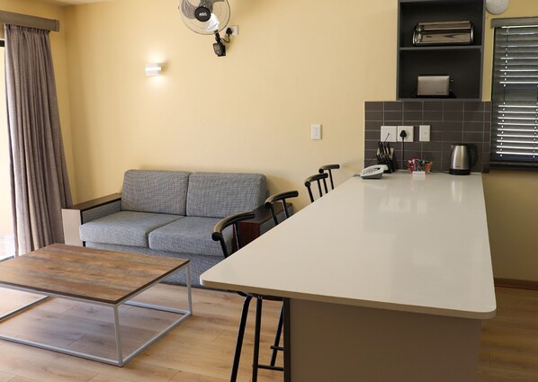 Una cocina moderna con una isla central, un sofá gris y una mesa de comedor.