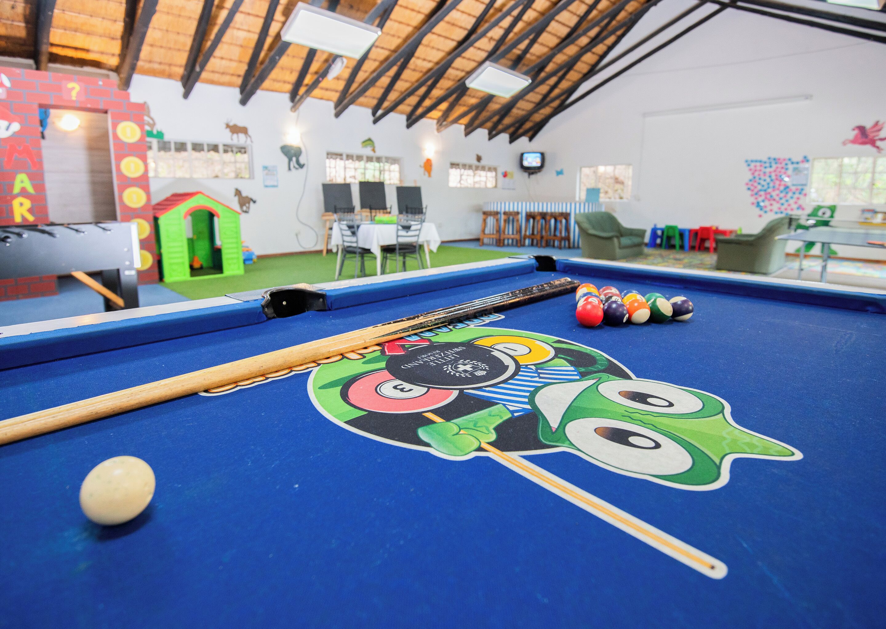 A pool table with a colorful design, a pool cue, and billiard balls.