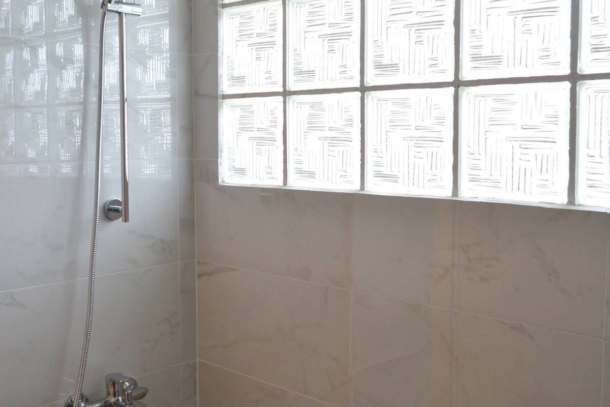 Un espacio de ducha con mampara de vidrio y ducha de mano.