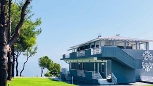 A two-story building with a balcony, labeled "Aelia View Studio," situated on a grassy slope with trees in the background. - Aelia Sea View Studios (Kassandra)