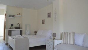 A bedroom with a bed, bedside tables, a desk, and a small kitchenette. - Aelia Sea View Studios (Kassandra)