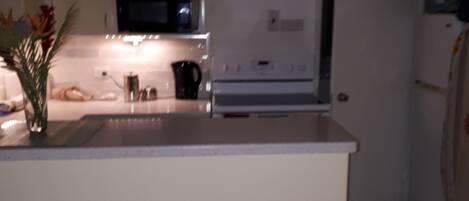 A kitchen with white cabinets, a microwave, a stove, and a refrigerator.