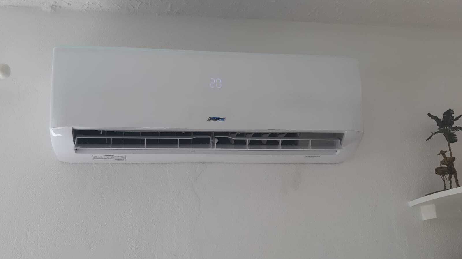 Un aire acondicionado blanco, fijado a la pared, con una pantalla digital que muestra la temperatura.