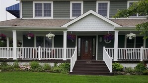 A two-story house with a front porch, a dark brown front door, and a number '1234' on the steps. - Beautiful Colonial Mint Condition Summer House Walking Distance to Beach (Laurel)