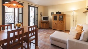 A dining area with a table and chairs, a television on a stand, a cabinet, and a sofa. - NICE APARTMENT in the CENTER of TOSSA (Tossa de Mar)
