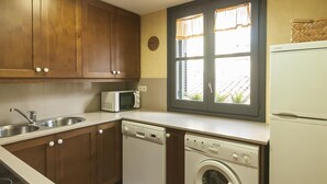A compact kitchen with wooden cabinets, a microwave, a dishwasher, and a washing machine. - NICE APARTMENT in the CENTER of TOSSA (Tossa de Mar)