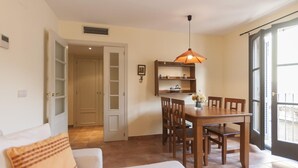 A dining area with a wooden table and chairs, a pendant light, and a small shelf with decorative items. - NICE APARTMENT in the CENTER of TOSSA (Tossa de Mar)