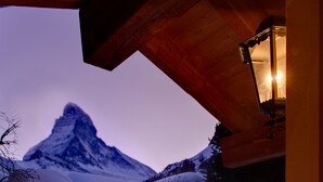 Une terrasse en bois offrant une vue sur une montagne enneigée au crépuscule.