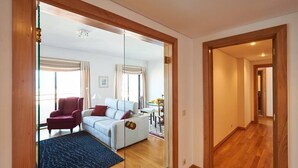 Un salon moderne avec un canapé, un fauteuil et une cloison en verre.