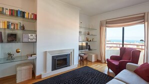 Un salon moderne avec une cheminée, une bibliothèque, un téléviseur et une vue sur la mer.