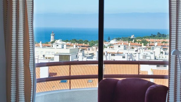 Un balcon offrant une vue sur le paysage urbain de la côte, avec des bâtiments et un phare.