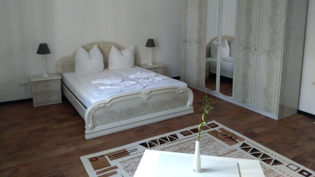 A bedroom with a bed, nightstands, a wardrobe, and a vase with a plant. - Villa Birkenfeld (Birkenfeld)