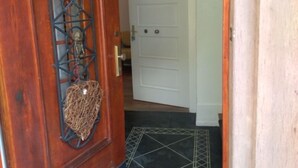 A wooden door with a decorative metal grille and a hanging birdcage. - Villa Birkenfeld (Birkenfeld)